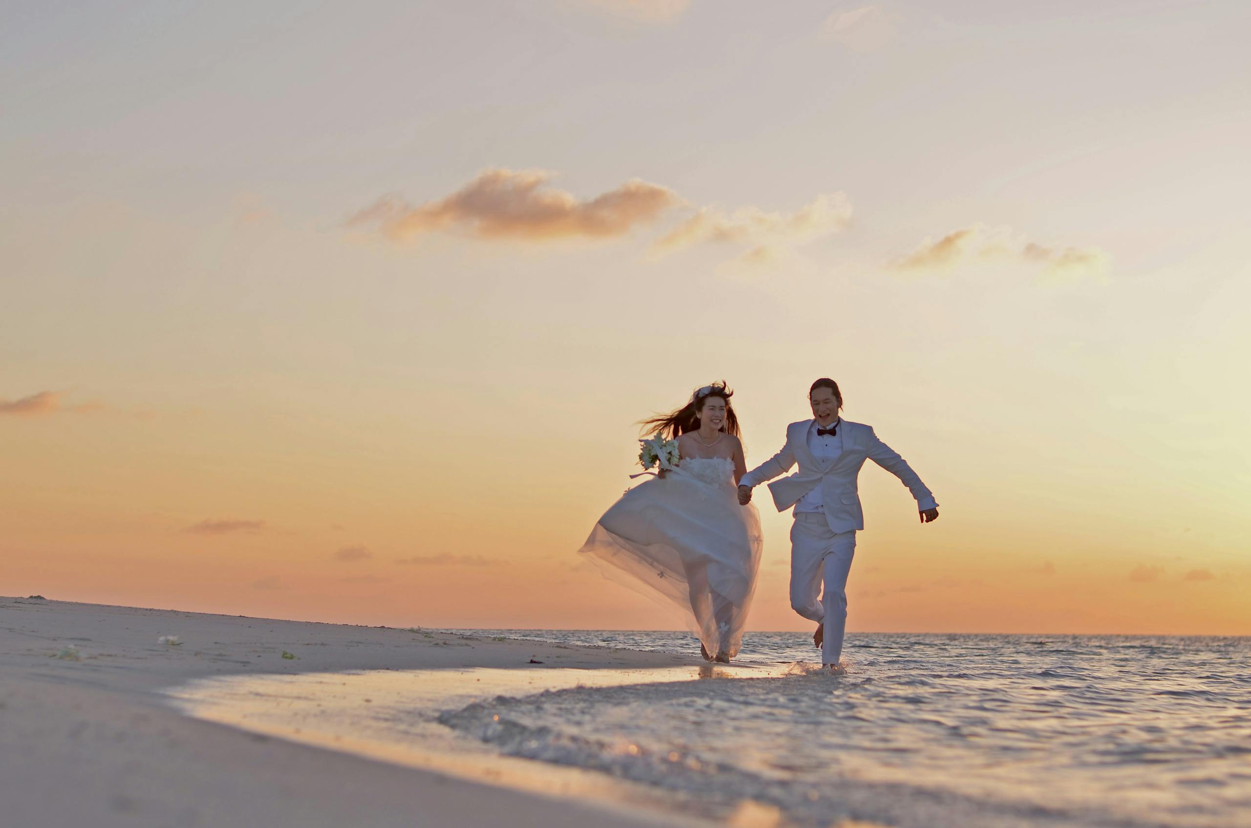 Newlywed couple joyfully running on a sandy beach during a beautiful sunset in costa del sol whit my beach wedding.